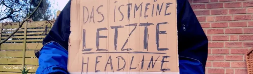 Ein Pappschild mit der Aufschrift 'Das ist meine letzte Headline' – eine provokante Anspielung auf die Frage, ob KI Texter-Jobs killt.