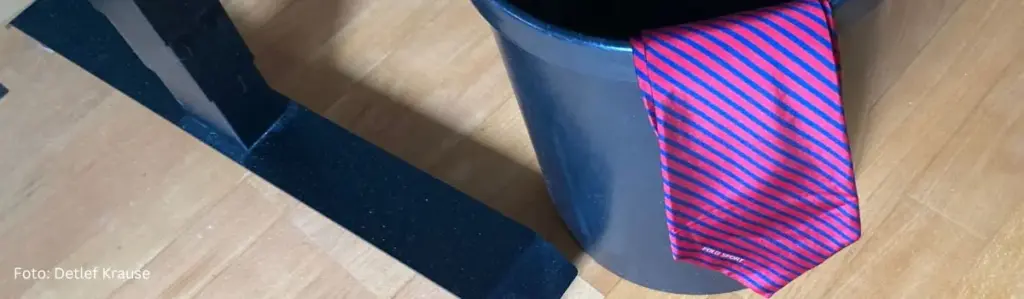 Eine klassische Business-Krawatte hängt an einer Mülltonne – Symbol für den Abschied vom Konzern-Sprech und den Start in die authentische Selbstständigkeit als Berater.