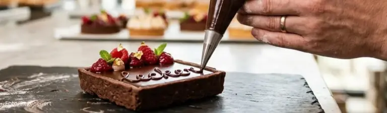 Törtchen auf das mit einer Konditorenspritze das Wort "lecker" geschrieben wird