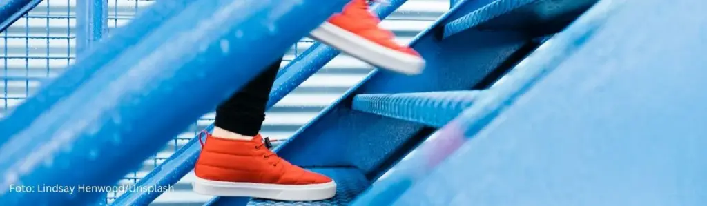 Webseiten texten: Texten fürs Web – symbolisiert durch eine Person mit roten Sneakers, die eine blaue Treppe hinaufsteigt.