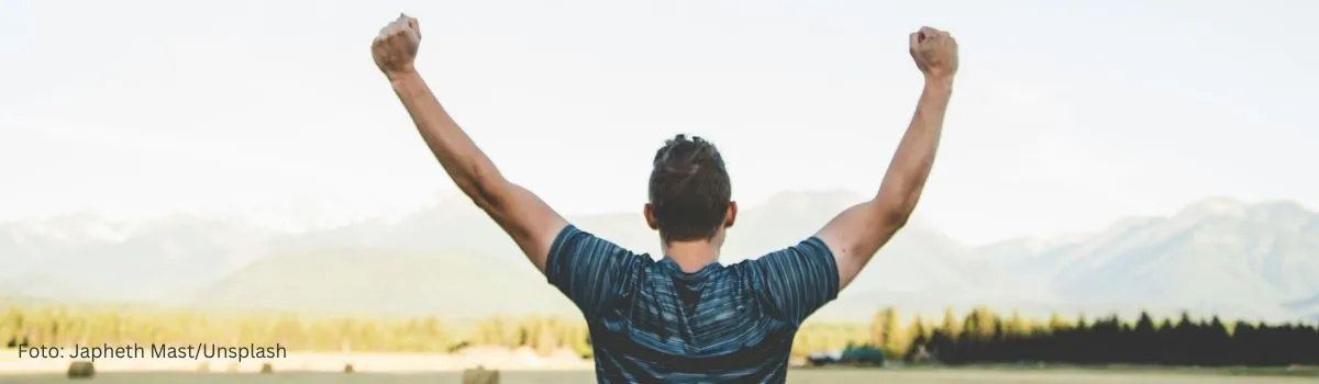 Website optimieren für Conversion – symbolisiert durch eine jubelnde Person vor einer Landschaft, die Erfolg und Wachstum darstellt.